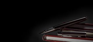 黑色背景一叠本子与钢笔高清