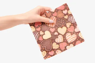 手拿着棕色布满爱心的餐巾纸免抠