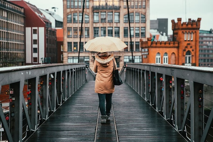 雨天，一个拿着雨伞的女人在桥上走着