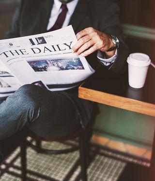 坐在凳子上看日报的人