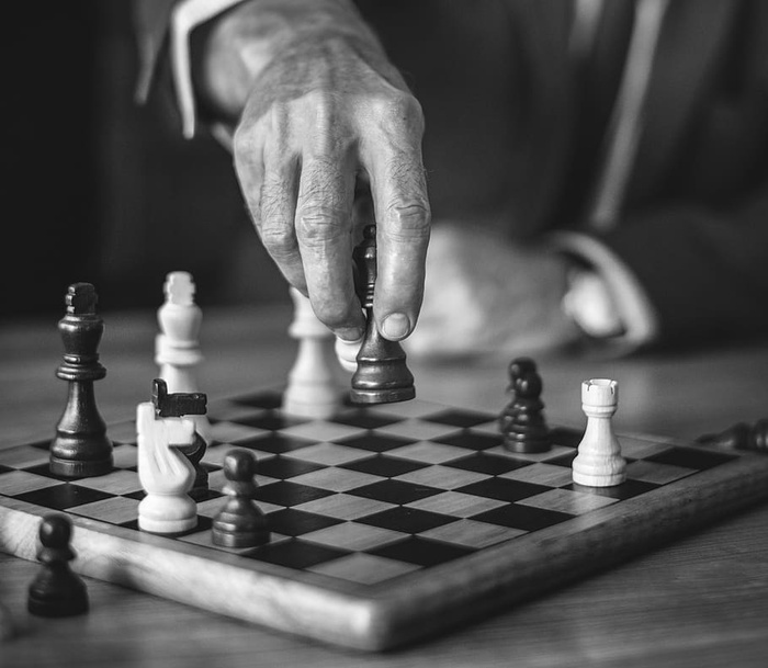 拿着棋子的人的灰度照片