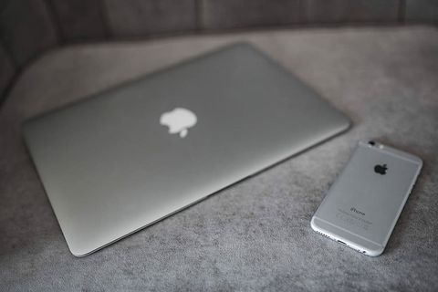 优雅的灰色沙发，配有笔记本电脑、iPhone和杂志