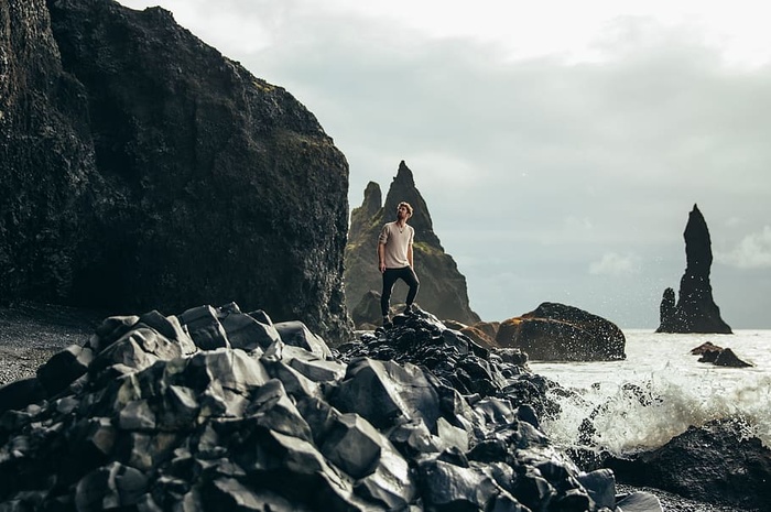 一个年轻的高加索徒步旅行者在海边的火山岩上