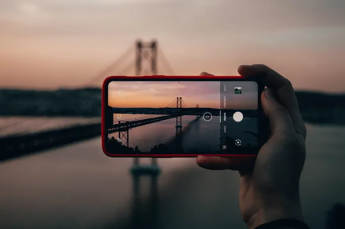 日落时用红色智能手机拍摄的大桥照片