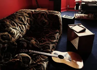 斜靠在棕色天鹅绒沙发上的棕色原声吉他