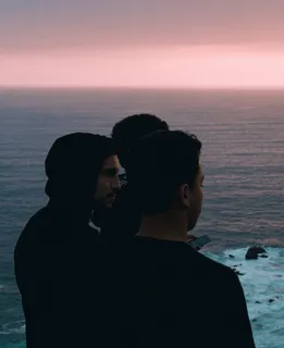 男人穿着黑色套头衫和黑色圆领上衣，看向右侧