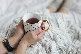 床上女人手拿书和咖啡的软照片