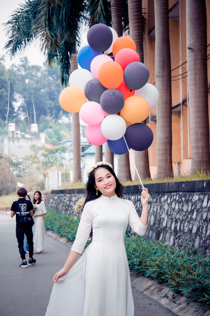 一名身穿白色连衣裙的女子手持一捆气球