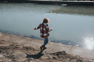 白天，穿着红白格子衬衫的人朝河边跑去