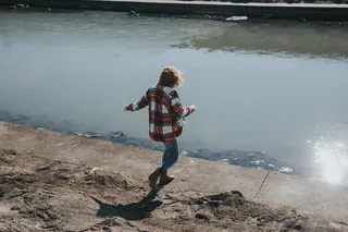 白天，穿着红白格子衬衫的人朝河边跑去