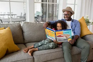 坐在灰色沙发上拿书的男人