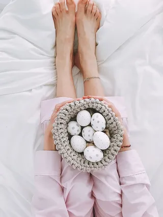 拿着灰色钩针碗和七个彩蛋的女人