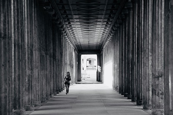 人在柱子附近行走的灰度照片