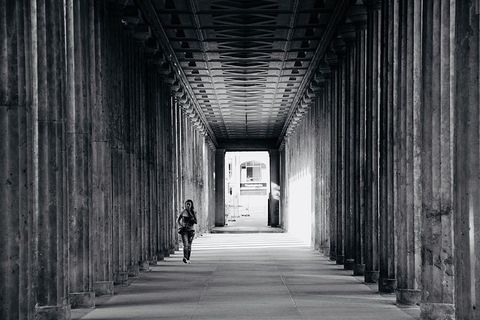 人在柱子附近行走的灰度照片