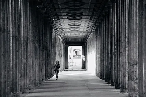 人在柱子附近行走的灰度照片