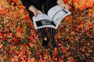 以五颜六色的树叶为背景，拿着格拉夫康夫书的女孩