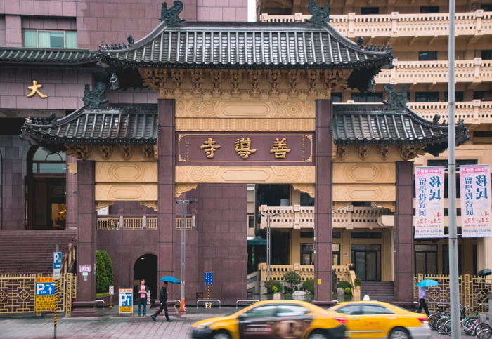 一名男子在寺庙附近拿着雨伞散步