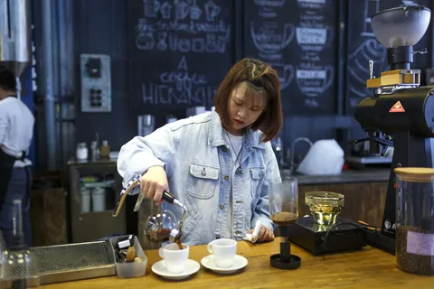 在杯子上倒咖啡的女人 在杯子上倒咖啡的女人