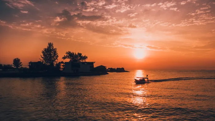 黄金时段水边房屋和树木的剪影