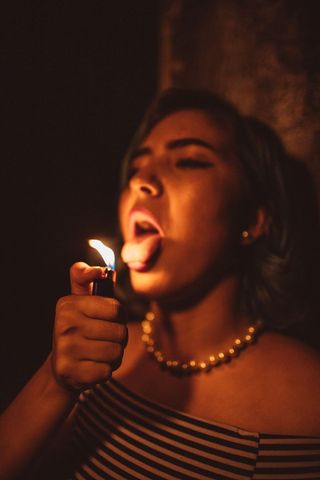 拿着点燃的一次性打火机露出舌头的女人