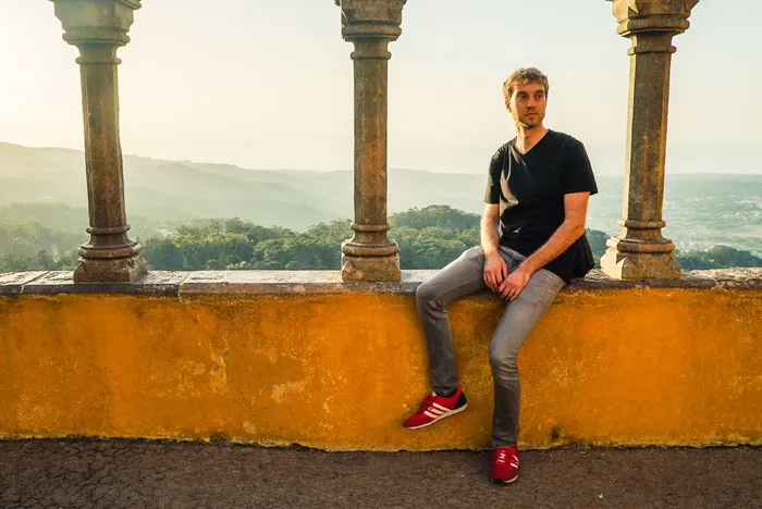 坐在混凝土平台上的男子，俯瞰群山