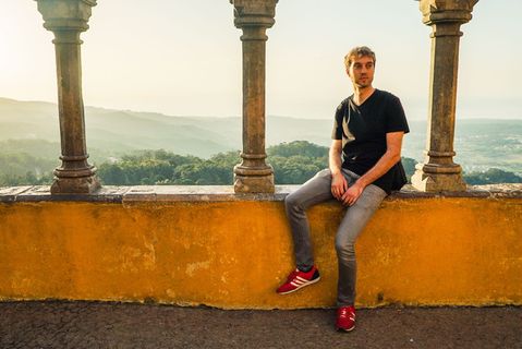 坐在混凝土平台上的男子，俯瞰群山