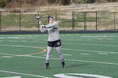 穿着灰色运动衫的女子白天打长曲棍球