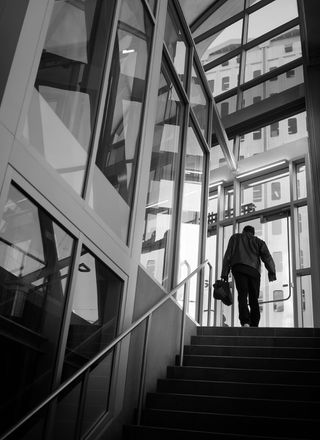 一名男子使用大楼内楼梯的灰度照片