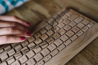 女性手在无线木质键盘上打字的特写
