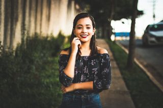 右手放在路边脸颊上微笑的女人