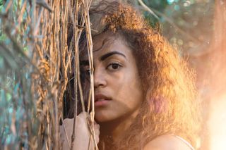 持棕色树叶树照片的女子