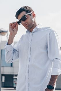 一名男子穿着白色衬衫，戴着墨镜
