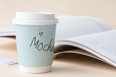 书旁的白色和蓝色摩卡杯