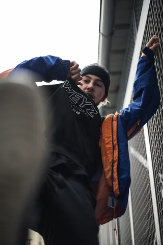 身穿黑色衬衫和蓝色夹克的男子手持灰色金属栅栏