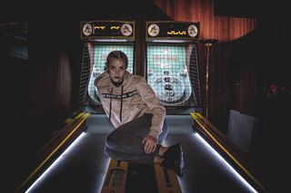 穿着灰色套头衫连帽衫坐在街机上的女人