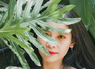 在树叶后面微笑的女人