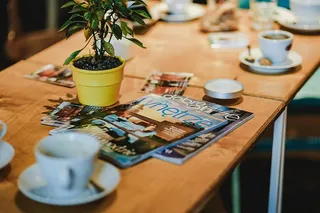 桌上放着笔记本电脑、智能手机、杂志和咖啡