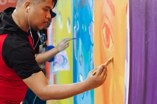 身穿红黑衬衫拿着油漆刷的男子