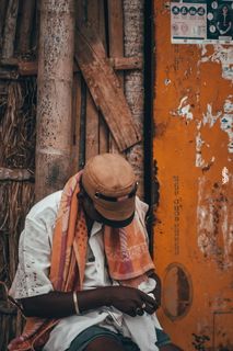 身穿白色上衣的男子在棕色墙壁旁拿着布