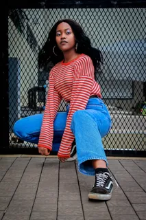 身穿红白条纹长袖衬衫和蓝色牛仔裤的女子蹲姿照片