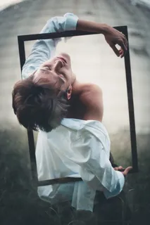 男子身穿白色长袖衬衫，手持矩形框