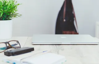 一副rayban眼镜，外置硬盘，绿色植物，家庭工作站，在家工作，macbook pro，现代简约工作空间，科技