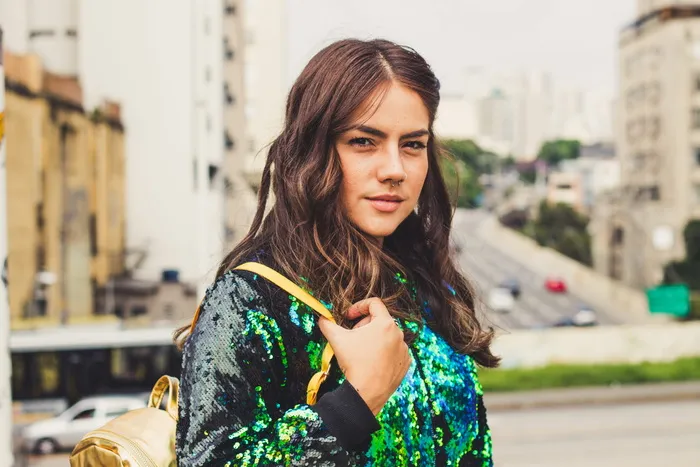 身穿亮片夹克、背着背包的女子肖像照