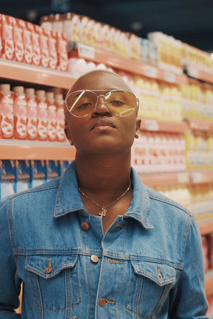 身穿蓝色Chambray纽扣衬衫和黄色镜片飞行员式太阳镜的女士