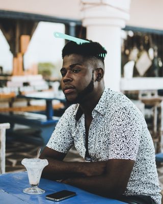 照片中的男子穿着白色纽扣领衬衫，头发上戴着梳子，正在吃冰淇淋