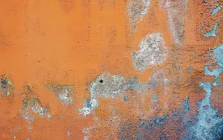漆成橙色的旧墙有裂缝和锈迹