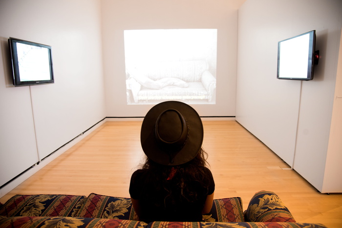 坐在红绿绒沙发上的女人，面对着明亮的房间