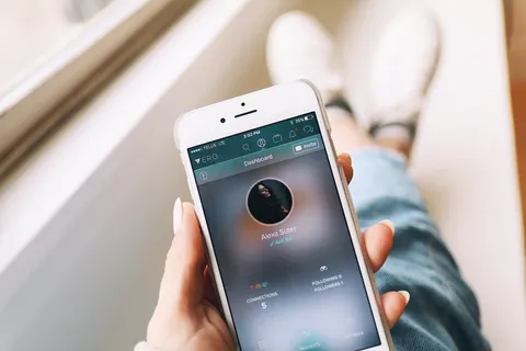手持手机的人打开银色iPhone 6,显示用户档案 手持手机的人打开银色iPhone 6,显示用户档案