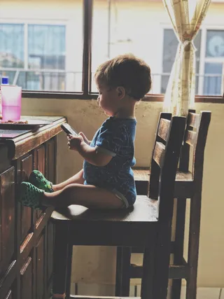 坐在椅子上拿着智能手机的男孩