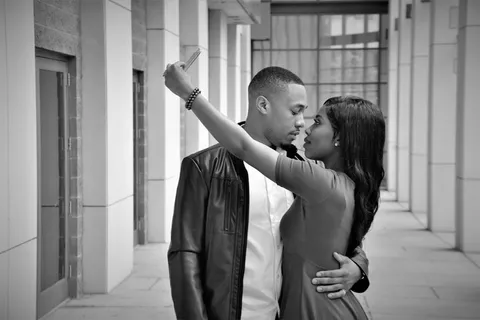 男人抱着用手机拍照的女人